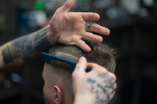 pexels-photo-1570807-1570807 Close-up of a tattooed barber giving a stylish haircut indoors, highlighting modern grooming techniques.